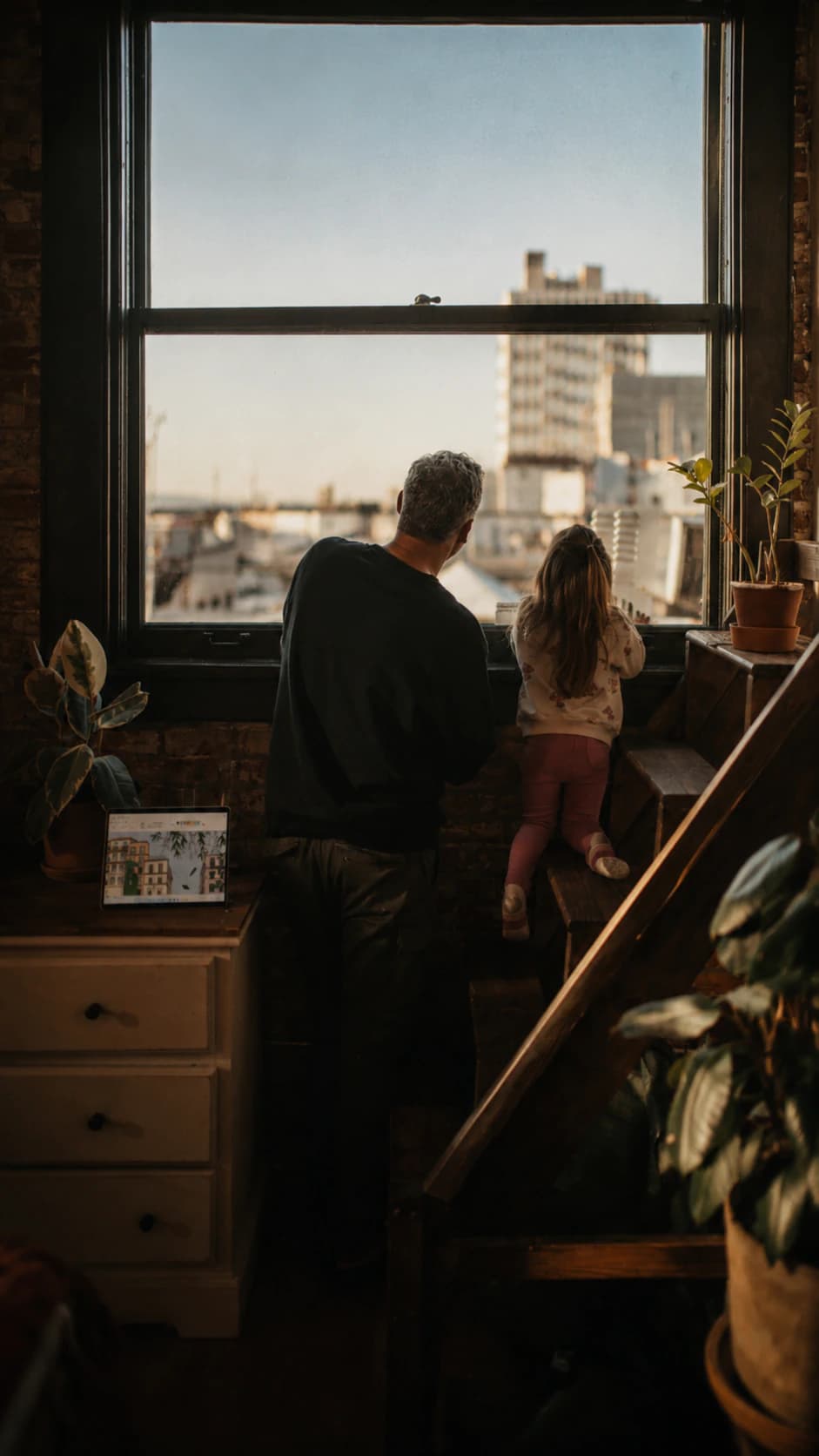 Un padre e sua figlia guardano insieme fuori dalla finestra